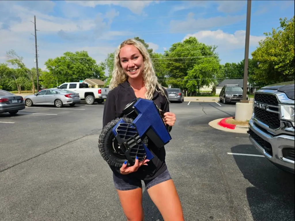 Shelby holding a blue electric unicycle